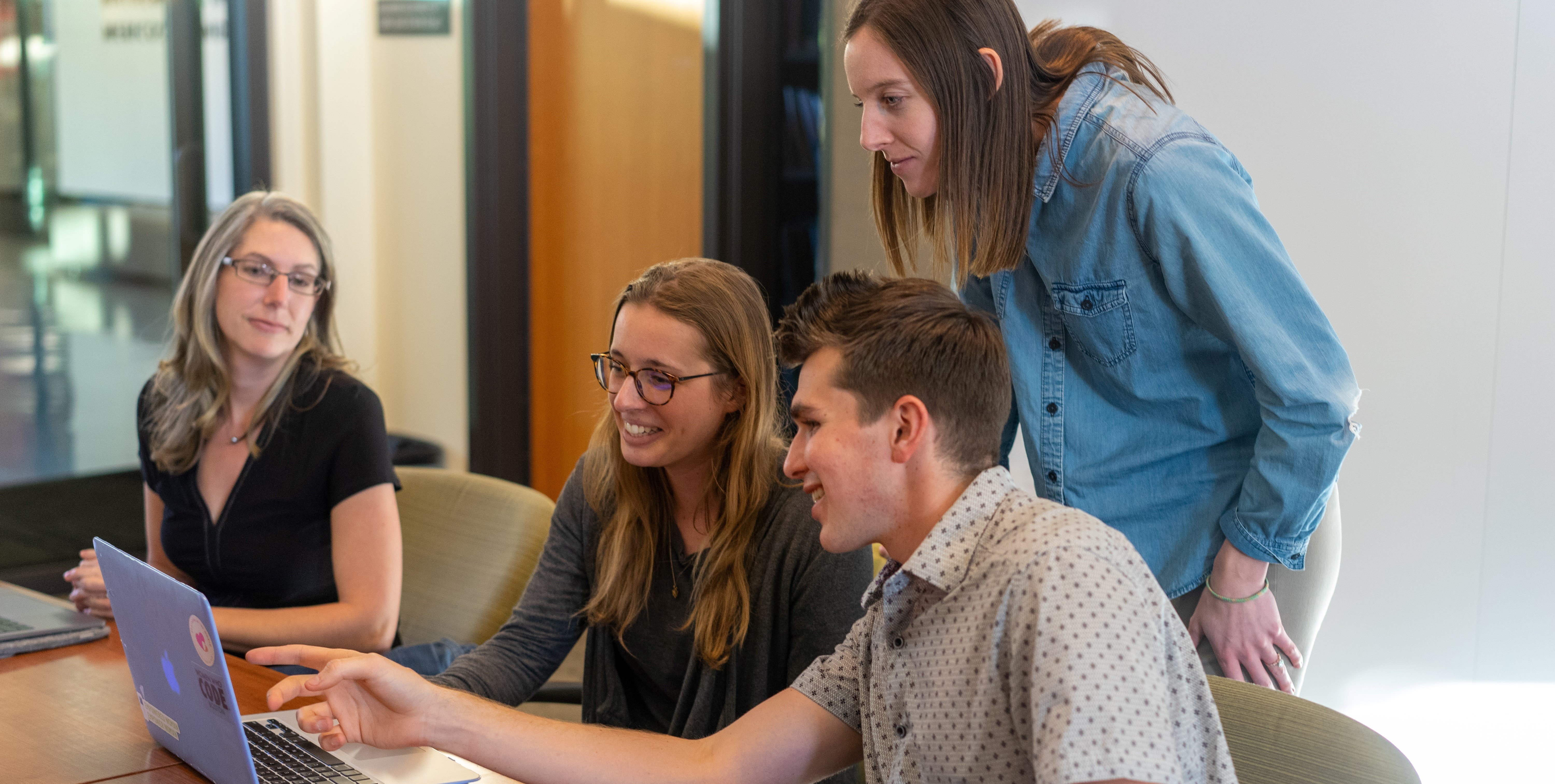 Colleagues collaborating around a laptop