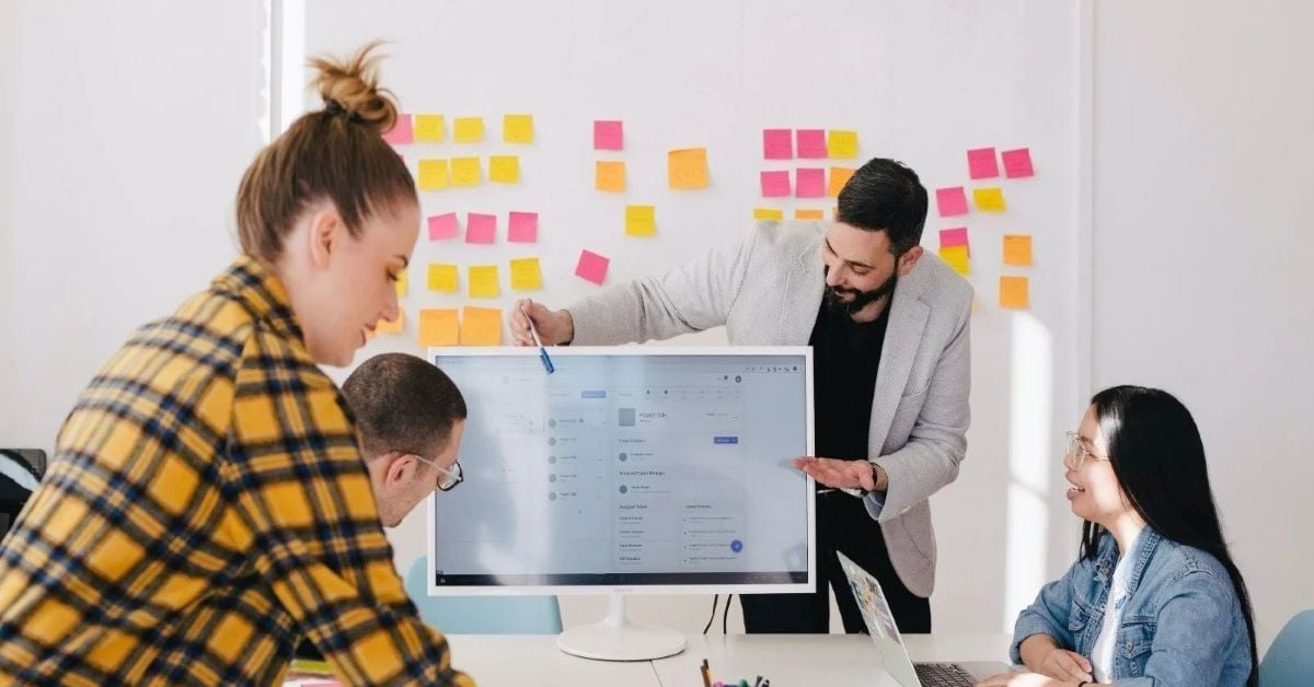 Colleagues collaborate around a monitor